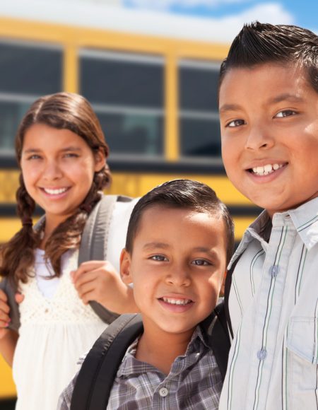 Young Hispanic Boys and Girl Walking Near School Bus.